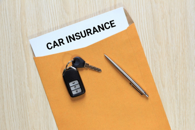 car insurance in envelope with pen and car key remote control on table 