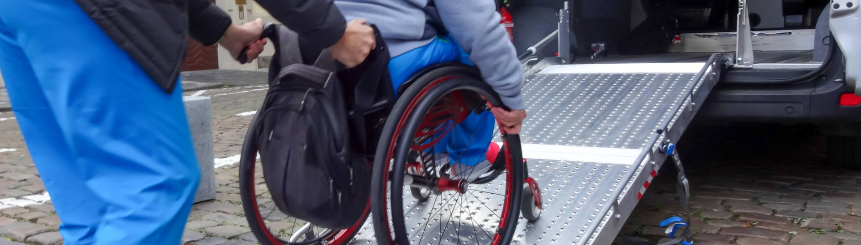 young man pushing the wheelchair inside the van